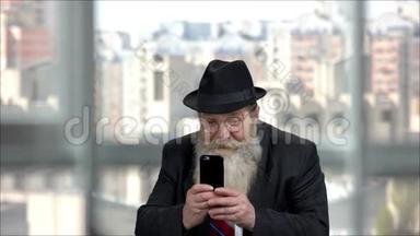 表情开朗的长胡子老人用手机拍照。